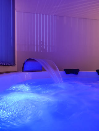 Primer plano de una cascada de agua fluyendo en una bañera de hidromasaje iluminada con luz led azul